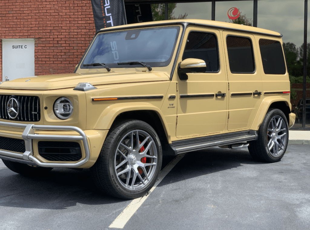 A yellow mercedes benz parked in the parking lot.